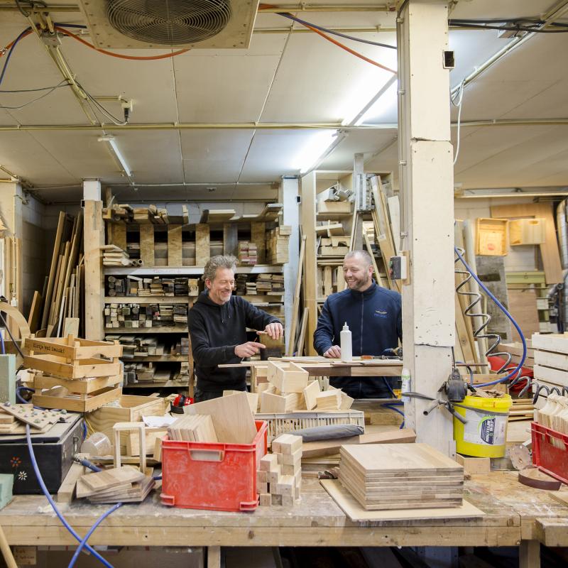 Twee timmermannen in hun atelier gevuld met verschillende soorten planken