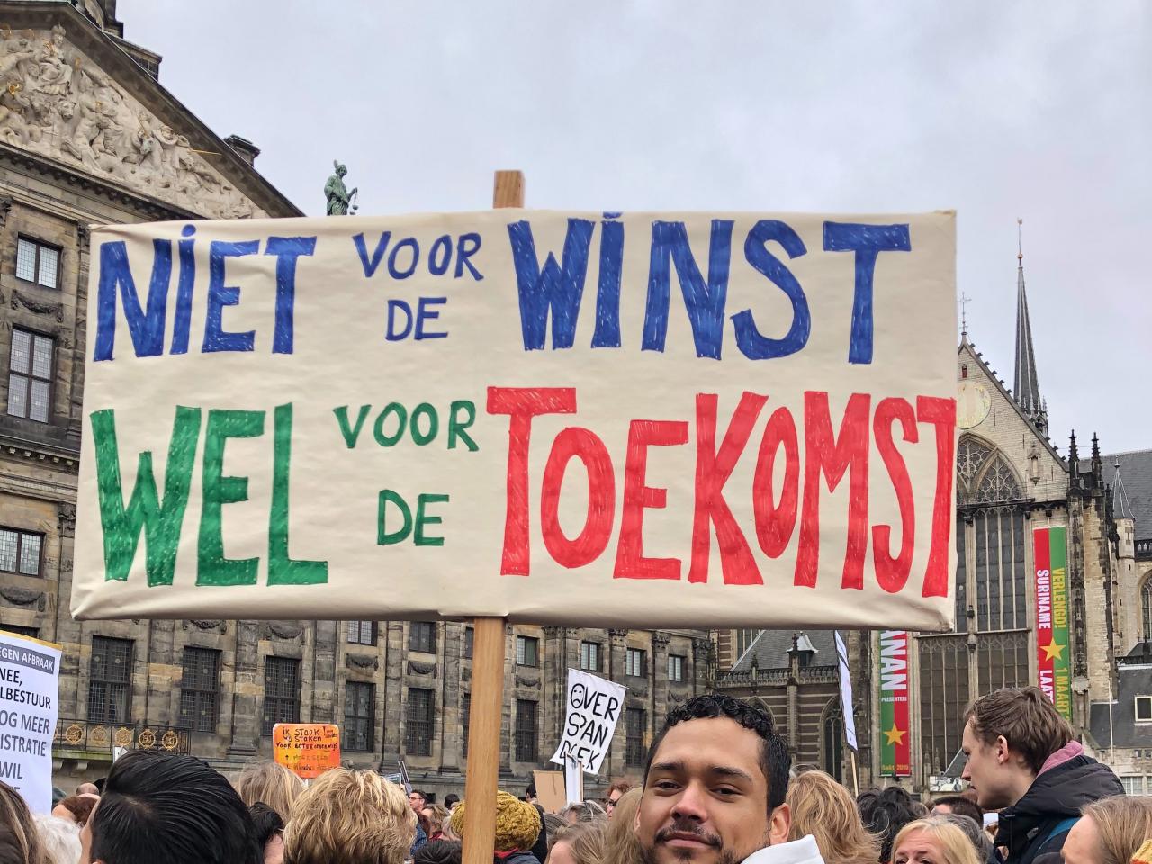 Een demonstrant op een onderwijsprotest houdt een bord vast waarop 'Niet voor de winst, wel voor de toekomst' staat.
